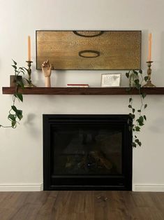 a fireplace with some candles on top of it and a painting above the fire place