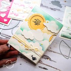 a hand holding a small card with clouds on it and some other cards in the background