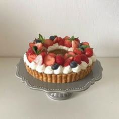 a cake topped with fresh strawberries and blueberries on top of a silver platter