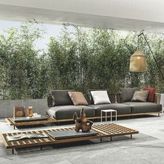 a living room with couches and tables in front of bamboo trees on the wall