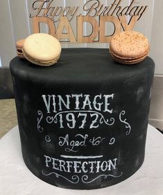 a black cake with white writing and cookies on top