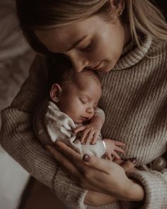 a woman holding a baby in her arms while she is breastfeeding it's head