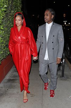 a man and woman dressed in red are walking down the sidewalk holding hands with each other