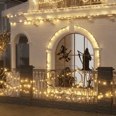 a white building with christmas lights on the windows and balconies in front of it