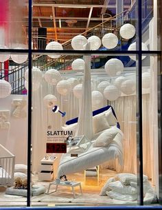 a store window with white furniture and hanging lights