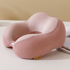 a pink pillow sitting on top of a table next to a book and magazine holder