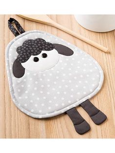 a sheep shaped pot holder sitting on top of a wooden table