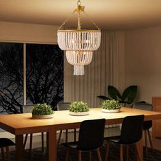 a chandelier hanging over a wooden table in a room with black chairs and windows