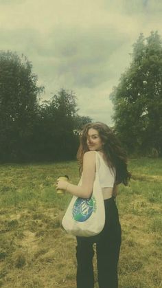 a woman holding a bag in the middle of a field