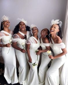 a group of women in white dresses standing next to each other and smiling at the camera