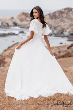 a woman in a white dress standing on top of a hill