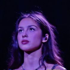 a woman with ear buds on her ears looking up at something in the dark sky