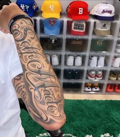 a man with a tattoo on his arm in front of a store display filled with baseball caps