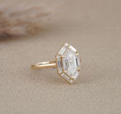 a diamond ring sitting on top of a sandy surface