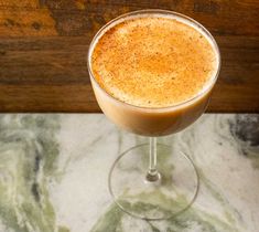 a close up of a drink in a wine glass on a table with marble counter top