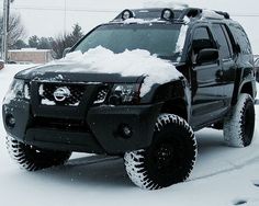 a black truck is covered in snow on the street