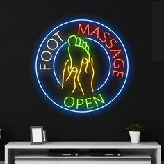 a neon sign that says foot massage open on the wall next to a white cabinet