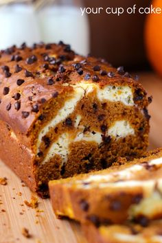 a loaf of cake sitting on top of a wooden cutting board next to an orange pumpkin