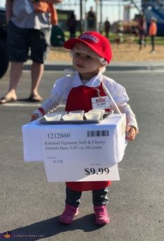 a small child in a red hat and white shirt holding a box of donuts