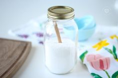 a glass jar filled with white sugar and a wooden spoon on top of a table