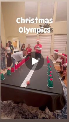 a group of people standing around a table with cups on it and the words christmas olympics in front of them