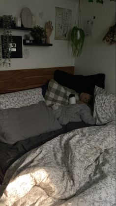 an unmade bed with pillows and blankets on top of it in a room filled with plants