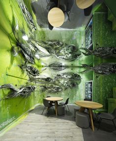 a green room with two tables and chairs in front of the wall that looks like an abstract painting