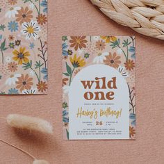 the wild one birthday party is set up with flowers and leaves on pink paper, next to a wicker basket