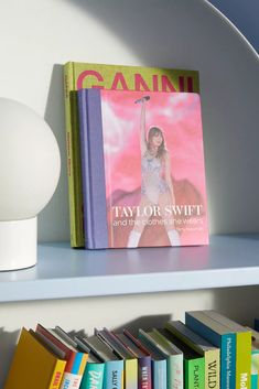 a book shelf with several books on it and a lamp in the corner next to it