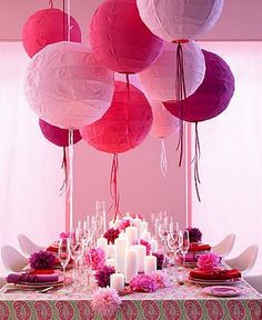 a table topped with lots of pink and white paper lanterns hanging from the ceiling above it