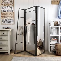 an open closet with clothes on hangers and other items in the room next to it