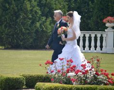 the bride and groom are walking in front of some flowers