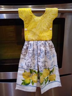 a yellow top and white shorts hanging from the handle of an oven door in front of a stainless steel stove