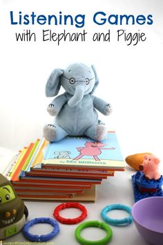 an elephant sitting on top of a pile of books next to toy rings and toys