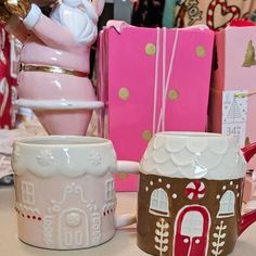 two coffee mugs sitting on top of a table next to boxes and other items