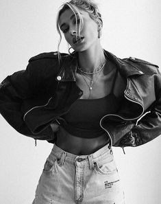 black and white photograph of a woman wearing a leather jacket, cropped top and ripped jeans