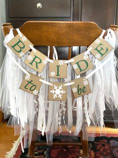 a bride to be banner on a chair with white tulle and snowflakes