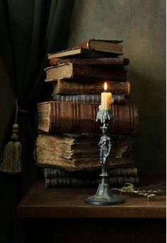 a stack of books with a lit candle on top