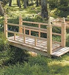 a small wooden bridge in the middle of some grass