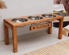 a wooden table with three bowls on it and a dog bowl holder underneath the table