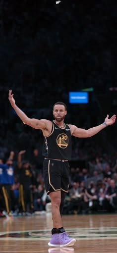 a man standing on top of a basketball court holding his arms up in the air