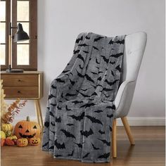 a living room with a white chair and black bat print blanket on top of it