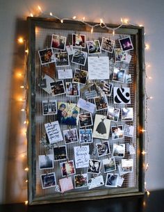 an image of a bulletin board with pictures on it and lights strung around the frame