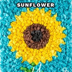 the sunflower is made out of blue and yellow shredded paper with leaves around it