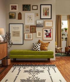 a living room filled with furniture and framed pictures on the wall above a green couch