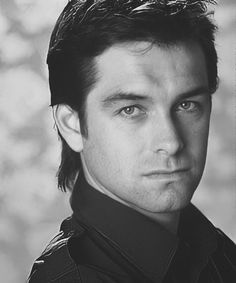 a black and white photo of a man with short hair wearing a collared shirt