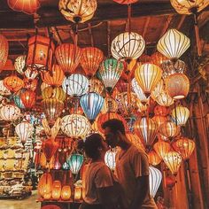 a man and woman standing in front of lots of lanterns