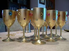 six gold wine glasses lined up on a table