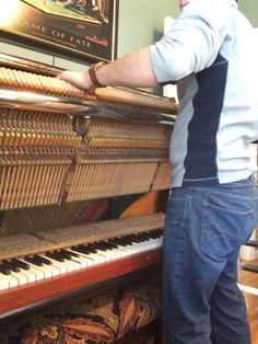 a man standing next to an old piano