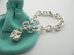 Offered for sale is a wonderful and super cute Tiffany and Co. Sterling Silver Signature Gift Box Charm bracelet. The piece is made from substantial and bright Tiffany silver, and yet retains a very feminine feel to it. Attached to its very substantial and bright Tiffany Silver charm bracelet is a super Cool Signature Gift Box Padlock charm. The Gift Box padlock charm opens and closes, and thus can be used as a charm on a necklace or as part of another charm bracelet! Super versatile piece! It i Cool Signatures, Silver Charm Bracelet, Tiffany And Co, Gift Pouch, Ribbon Bow, Charm Gift, Tiffany Heart, Heart Charm Bracelet, Super Cool